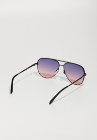 Schwarze Pilotenbrille mit einem abgestuften Glas, das von Lila nach Pink übergeht, ausgestattet mit dünnen Metallrahmen und schwarzen Bügeln.