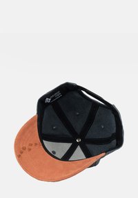 Black and brown suede baseball cap with a flat brim, multiple ventilation holes, and a branded label inside. Textured underside.