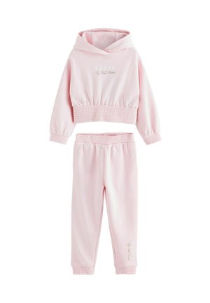 Ensemble deux pièces rose comprenant un hoodie court avec un ourlet élastique et un jogging à taille élastique assorti. Texte "BAKER par Ted Baker" affiché.