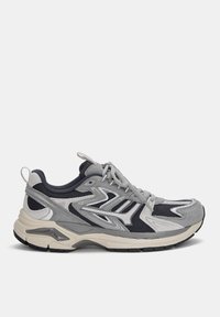 Szare i granatowe buty sportowe z siateczkową cholewką, teksturowanymi zamszowymi akcentami, odblaskowymi detalami oraz masywną podeszwą, z łagodnie zakrzywioną podeszwą.