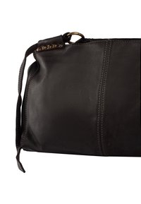 Sac à main en cuir noir avec une texture lisse, doté d'une fermeture zippée, de clous décoratifs en métal et d'une bandoulière pour le port.