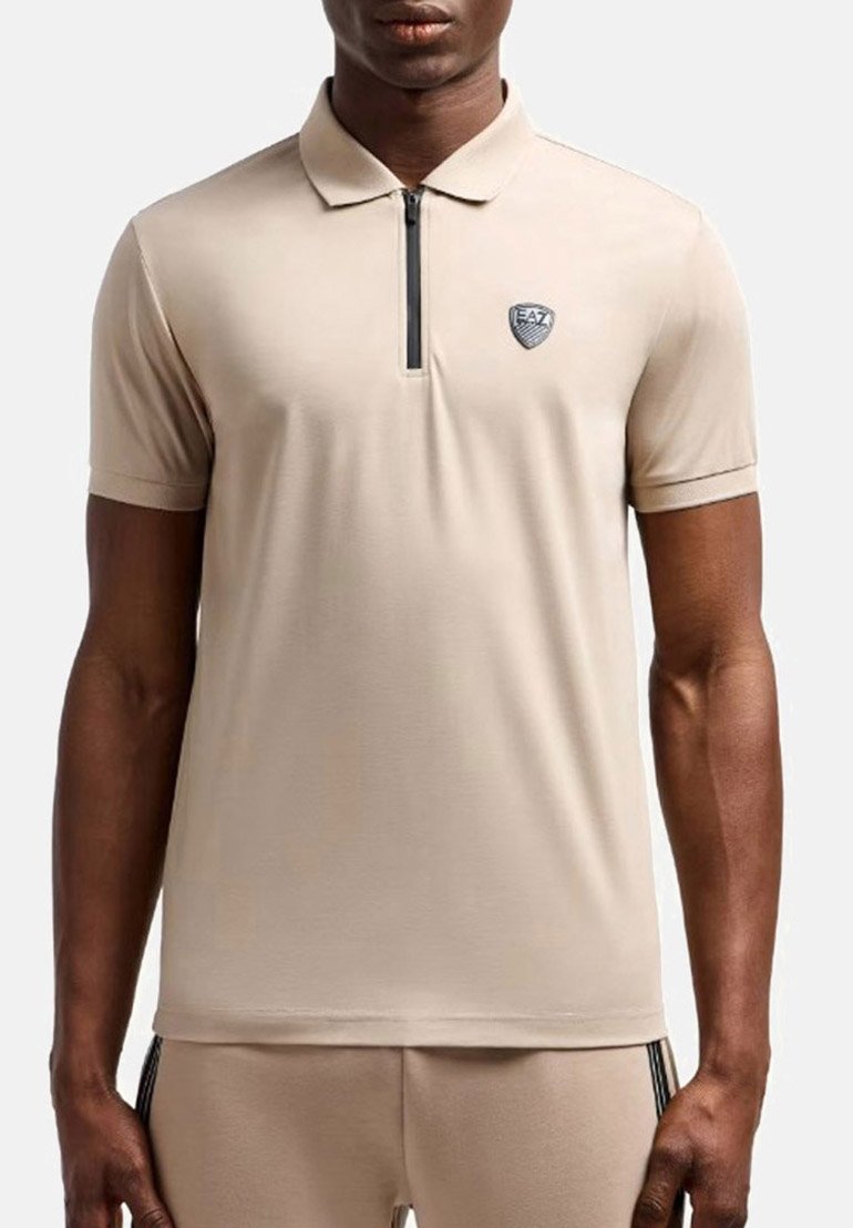 Polo beige con maniche corte, colletto con zip e logo EA7. Realizzato in tessuto liscio con una vestibilità aderente e dettagli minimi.