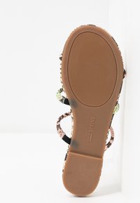 Semelle de sandale avec dessous en caoutchouc marron texturé et brides imprimées serpent multicolores visibles sur les bords.