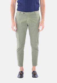 Chinos verde oliva con vestibilità slim, realizzati in cotone, dotati di chiusura a bottone e tasche. Abbinati a scarpe nere slip-on.