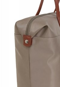 Borsa di stoffa beige con forma rettangolare, zip bronzo e dettagli in pelle marrone. Presenta un fondo piatto e cuciture decorative.