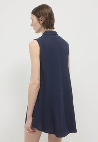 Abito senza maniche blu navy con colletto, realizzato in un tessuto liscio. Presenta una silhouette a campana e arriva sopra il ginocchio con un design pulito e semplice.