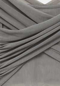 Tissu gris clair avec des plis drapés, présentant une surface texturée. Le design comprend des lignes douces et fluides ainsi qu'un superposition subtile.
