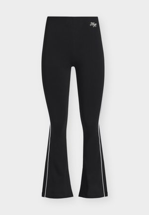 Μαύρο καμπάνα παντελόνι με λευκές πλαϊνές ρίγες και το κεντημένο λογότυπο «Hugo» κοντά στη ψηλή μέση, εμφανιζόμενο σε ανοιχτό φόντο.