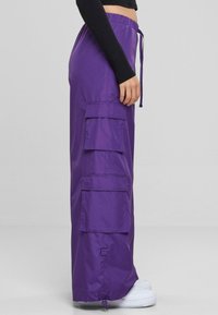 Cargo-Hosen in lebhaftem Lila, aus leichtem Material, mit mehreren Seitentaschen, elastischem Bund und Kordelzugverschluss.