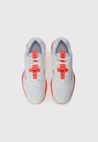 Chaussures de sport légères avec une tige en mesh blanche, des accents rouges et une semelle texturée avec un logo bien visible sur la languette.