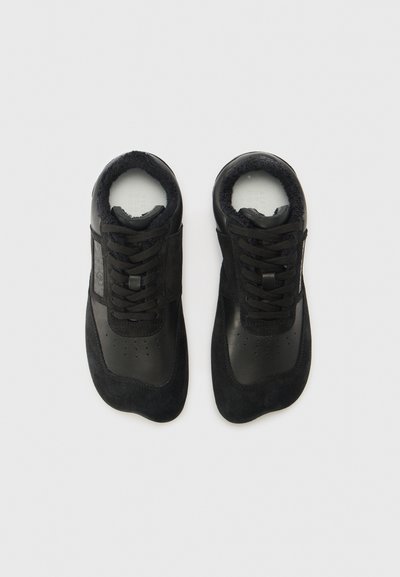 Crne tenisice koje sadrže kombinaciju kože i antilopa, okruglog vrha, vezanje sprijeda i mekanu, podstavljenu unutrašnjost od krzna.