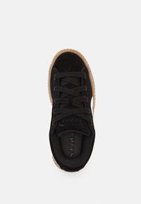 Czarne zamszowe sneakersy z gumową podeszwą, z przodem na sznurówki i wyściełanym kołnierzem. Logo widoczne na wkładce i boku.