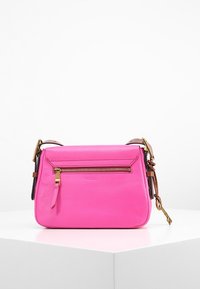 Bolso cruzado de cuero color rosa brillante con bolsillo frontal con cremallera, correa ajustable marrón y hebilla y charm de llave en tono dorado.