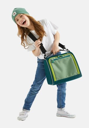 Grüne und türkisfarbene rechteckige Tasche mit zwei Reißverschlussfächern, Stoffträgern und einem reißverschlussförmigen Frontfach. Kind, das ein weißes Shirt und eine Mütze trägt.