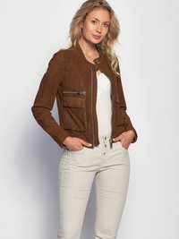 Bruin suède jasje met ritszakken, een ronde halslijn en een getailleerde pasvorm, gecombineerd met lichtgekleurde, slim-fit jeans.