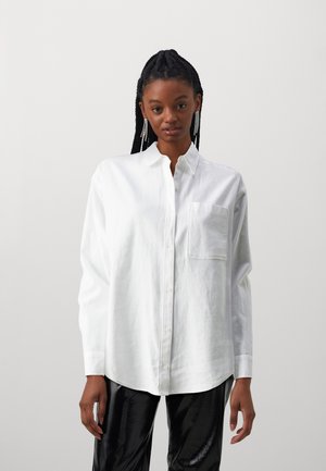 Chemise blanche à boutons en tissu léger, dotée d'une poche poitrine et de manches longues pour un ajustement décontracté.