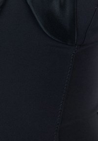 Tessuto nero con una superficie liscia, caratterizzato da un colletto in satin e cuciture decorative a zigzag lungo la cucitura.