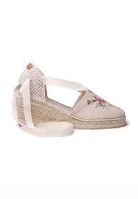 Wedge espadrille dengan kain beige terang, desain bordir bunga, sol jute anyaman, dan pita crisscross beige untuk dukungan pergelangan kaki.