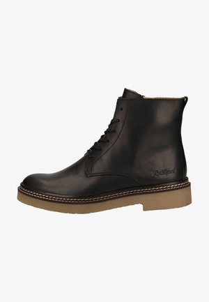Black leather ankle boot with lace-up design, rounded toe, contrast stitching, and tan rubber sole. Kickers logo embossed on side.