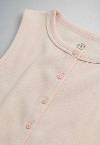 Chemise pour bébé en tissu côtelé rose clair avec encolure ronde et quatre petits boutons sur le devant, taille 6 ans.