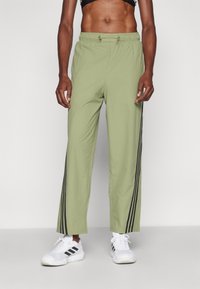 Světlé zelené sportovní kalhoty s elastickým pasem, se dvěma černými vertikálními pruhy po stranách, vyrobené z hladkého materiálu, zkrácený střih.