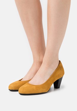 Yellow suede high-heeled shoes with a rounded toe and smooth texture. Black heel with a slight curve, featuring minimal stitching detail.