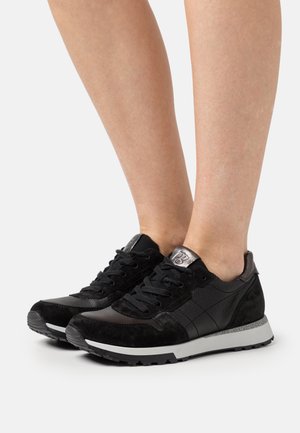 Baskets noires en mélange de daim et de cuir, avec un motif texturé, un bout rond, un design à lacets, et une semelle blanche contrastante.