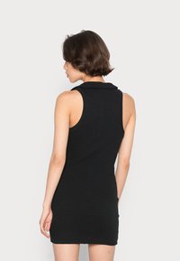 Vestido preto canelado sem mangas com gola e silhueta ajustada. Textura suave, comprimento até ao joelho, design minimalista sem padrões.