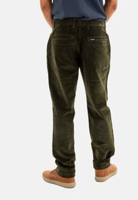 Pantalons en velours côtelé vert olive avec une coupe droite, dotés de deux poches arrière et d'une petite étiquette de marque près de la poche droite.