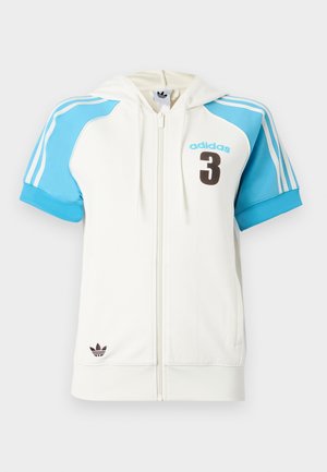 Fehér cipzáras kapucnis pulóver rövid kék ujjal, barna "adidas" logóval és "3" számmal. Csíkos díszítés a vállakon és a kapucnin.