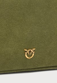 Τσάντα από σουέτ ελιάς με χρυσαφένιο μεταλλικό διακοσμητικό με θέμα πουλί και κυκλικό σχέδιο, με λεία υφή και επίπεδη σχεδίαση.