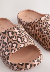 Sandale tip papuc cu imprimeu leopard, cu degetele larg deschise, realizate dintr-un material neted, cu o combinație de culori bej și maro închis.