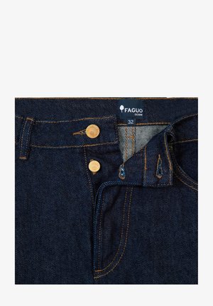 Jeans en denim bleu foncé avec une étiquette Faguo, deux boutons dorés, des coutures jaunes, et une poche avant visible avec une texture distincte.