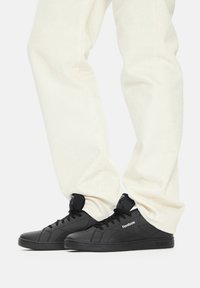 Mustad nahast ketsid lame tallaga, ümarate varvastega ja paeltega. Omavad reljeefset logo ja minimalistikku disaini. Kandmine valgete pükstega.