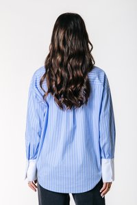 Blauw en wit gestreepte shirt met lange mouwen, voorzien van een gebogen zoom en contrasterende witte manchetten, gemaakt van lichte stof.