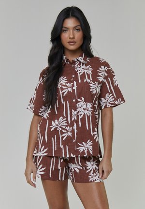Brunt linnedragt med en kortærmet skjorte med knapper og matchende shorts med hvidt palmetræsmønster og afslappet pasform.