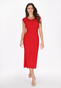 Abito rosso lavorato a maglia con silhouette aderente, maniche corte a campana e texture decorata. La lunghezza arriva fino al polpaccio con orlo scallop.