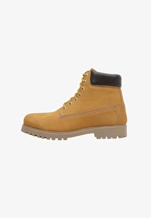 Bota de trabajo de cuero color canela con suela de tacos gruesos, cuello acolchado negro y cordones amarillos vista de lado sobre un fondo blanco.