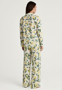 Das limonenbedruckte Loungewear-Set besteht aus langärmligen Oberteilen und weiten Hosen aus einem weichen, leichten Stoff mit einem cremefarbenen Hintergrund und grünen Akzenten.
