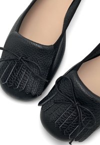 Black leather ballet flats with a textured finish, featuring a fringed design at the toe and a matching black bow accent.