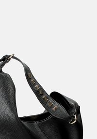 Borsa a tracolla in pelle nera con finitura testurizzata, caratterizzata da una forma strutturata e una tracolla impreziosita dalla scritta "PRIMANNI" in lettere metalliche.