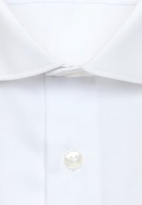 Gros plan sur le col et le bouton supérieur d'une chemise blanche, montrant la texture du tissu et les détails des coutures.