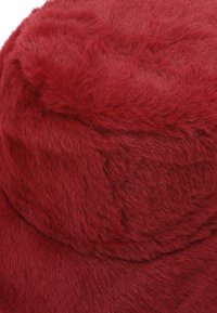 Cappello a secchiello in pelliccia sintetica rossa con superficie morbida e strutturata. Design con cima arrotondata e ampia tesa. Leggera lucentezza visibile sulla pelliccia.