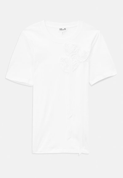Hvit kortermet t-skjorte laget av bomull med tre teksturerte blomsterapplikasjoner på forsiden, med rund hals og en avslappet passform.