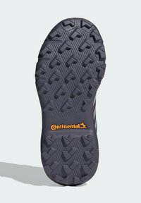 Semelle de chaussure gris foncé avec un motif de traction texturé et le logo "Continental" en orange. Présente des crampons angulaires pour la prise et la stabilité.