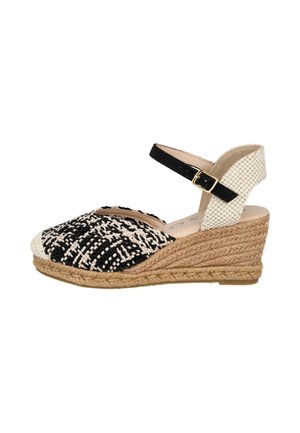 Sandalia de cuña con puntera cerrada tejida en negro y blanco, tira trasera beige tejida, tira en el tobillo negra con hebilla dorada y suela trenzada de yute.