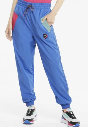 Pantaloni jogger leggeri blu con vita elastica, tasche rosse e verdi, cordino regolabile e una piccola toppa con logo sulla coscia.