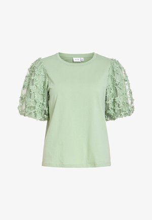 Világoszöld rövid ujjú felső kerek nyakkivágással és áttetsző, virágos csipke hímzésű fodros ujjakkal.