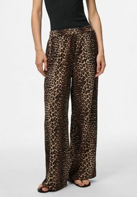 Pantalons larges à imprimé léopard en tissu léger avec une taille élastique, présentant une base beige et des taches brun-noir.