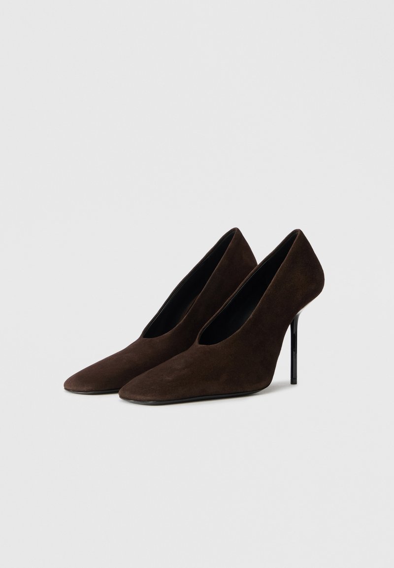 Scarpe con tacco alto in suede marrone, con punta affusolata, design elegante e tacco sottile nero. Texture liscia con silhouette minimalista.
